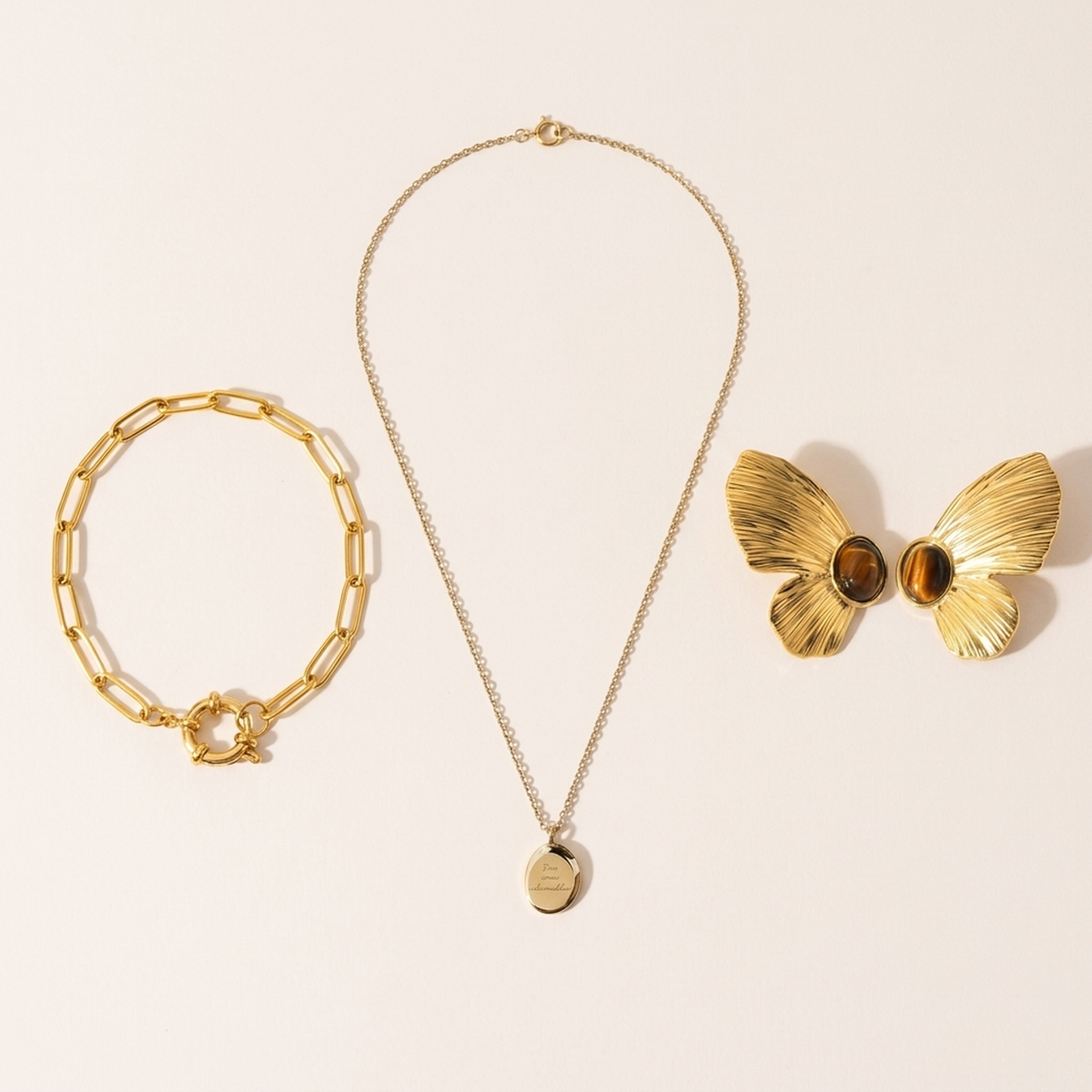 The bracelet, necklace and earrings laid flat on a pale surface