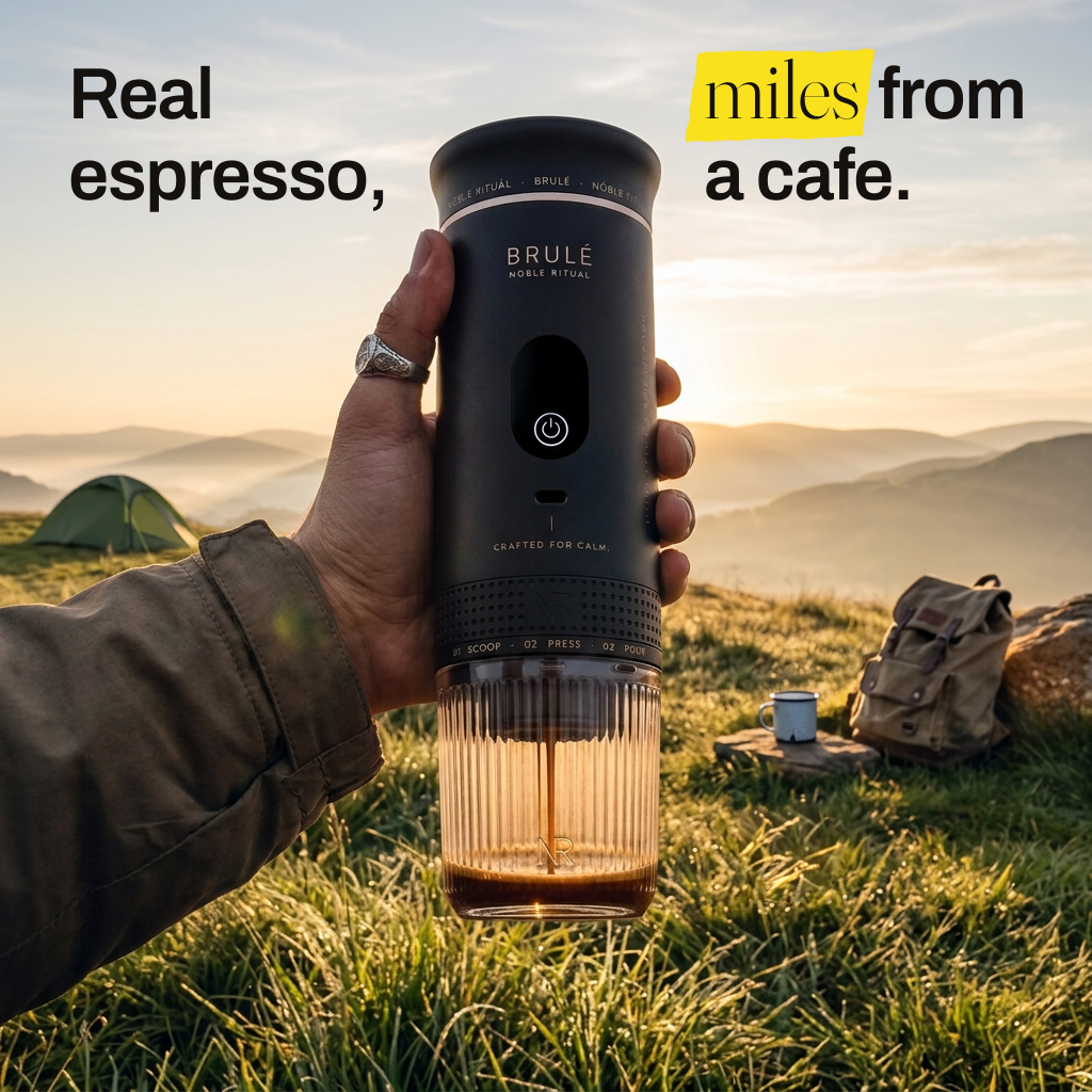A hand holds the Brulé portable espresso maker on a sunlit hillside while espresso drips into its glass. Real espresso, miles from a cafe.