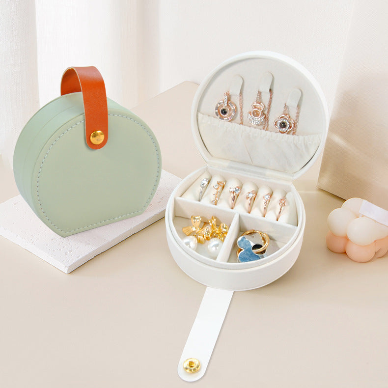 Round travel jewelry case open to show the ring roll and compartments