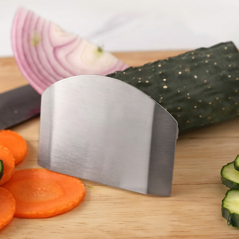A brushed stainless finger guard beside sliced cucumber and carrot