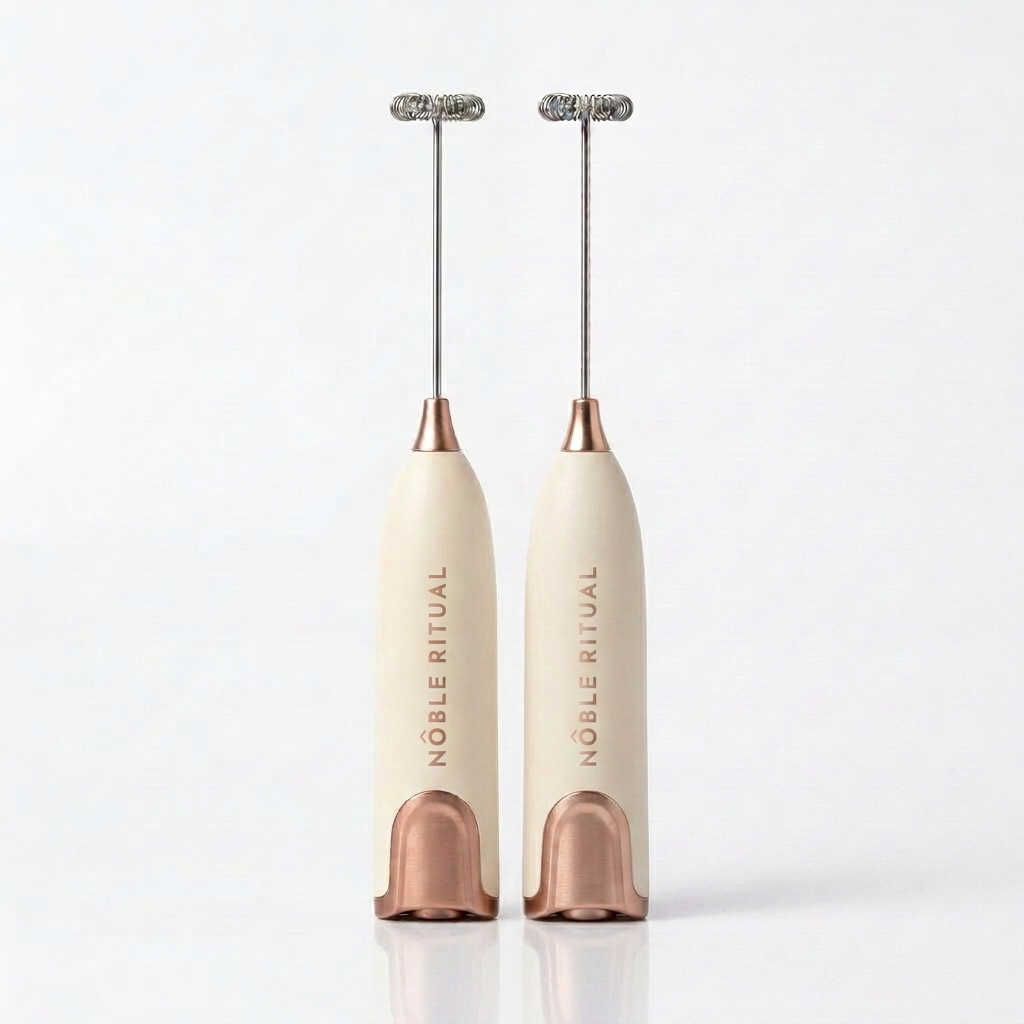 Noble Frothé Set of 2 in Two Cream: two cream frothers with rose-gold collars and bases, vertical rose-gold NÔBLE RITUAL wordmarks and coiled steel whisks