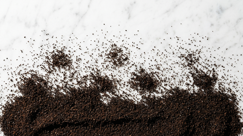 Ground coffee scattered across white marble.