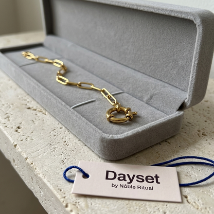 Close up of the grey flannel gift box with a gold-coloured bracelet clasp in the tray and a Dayset hang tag on the shelf