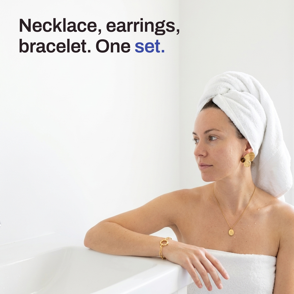 A woman with her hair in a towel at the edge of a tub, wearing the necklace, butterfly earrings and bracelet