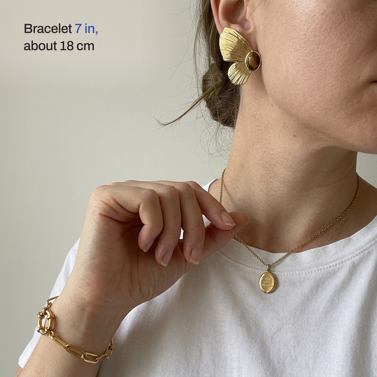 A woman wearing the butterfly earring, the oval pendant and the bracelet, with the bracelet length noted as 7 in, about 18 cm