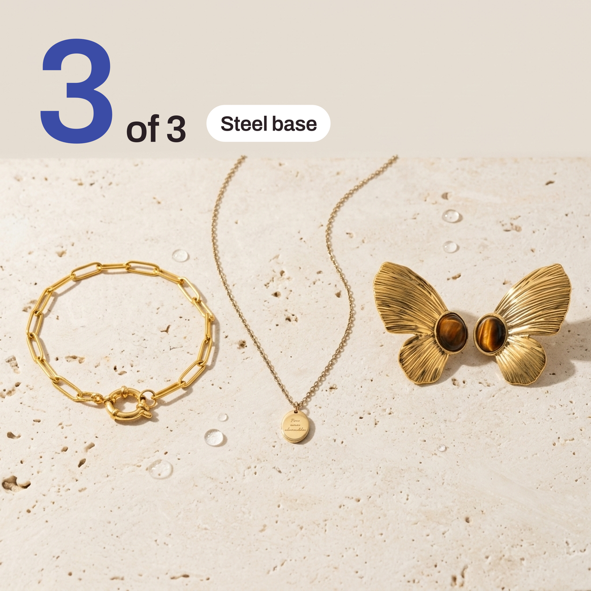 The bracelet, necklace and butterfly earrings laid flat on a stone surface, marked 3 of 3 with a steel base