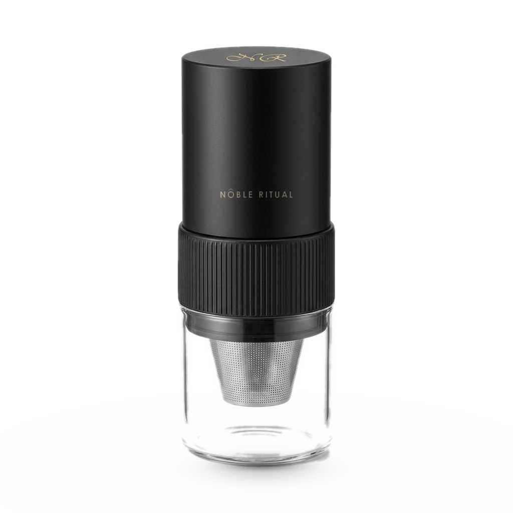 Noble Moulin portable electric coffee grinder with the Noble Ritual wordmark on the body, glass catch cup, on a white background