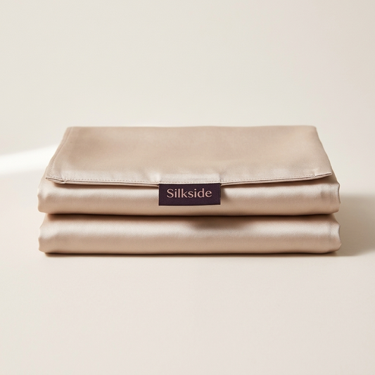 Two folded champagne mulberry silk pillowcases, light moving across the silk