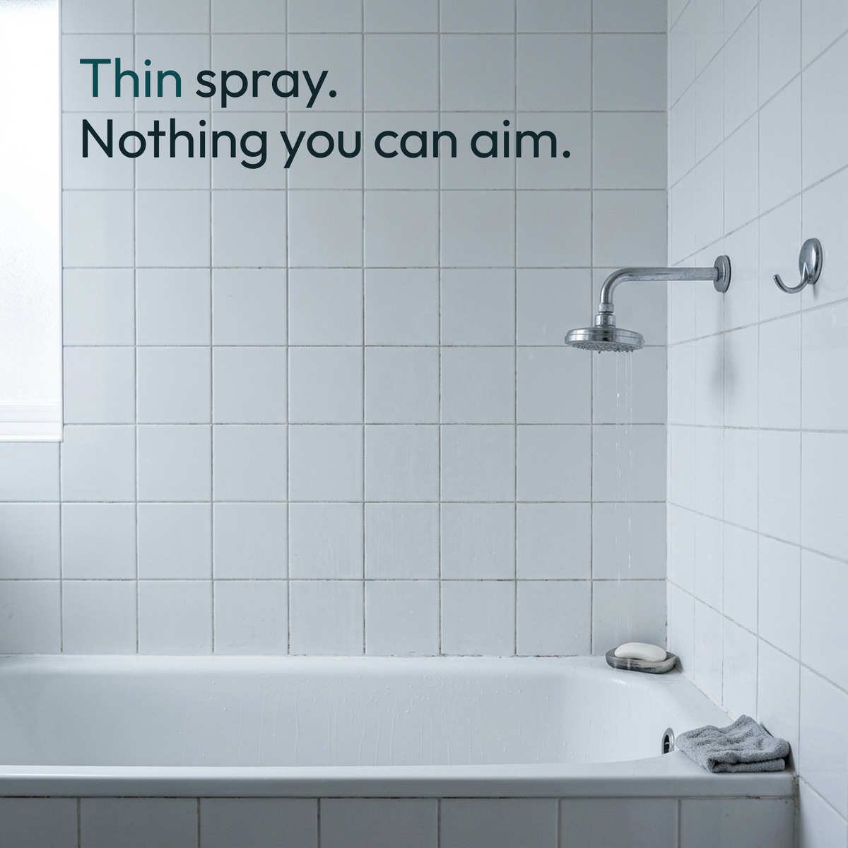A fixed wall showerhead dribbling thin streams over a tiled bathtub
